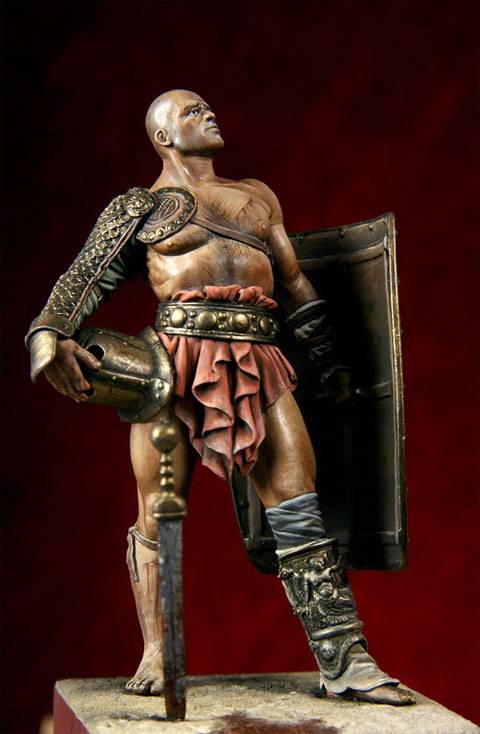 figura de un Gladiador en posici&oacute;n de descanso despu&eacute;s de haber ganado un combate, mirando hacia el  p&uacute;blico que llena el aforo en actitud desafiante.